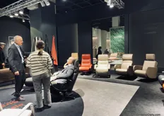 Visitors are testing the reclining armchairs of the German company Franz Fertig.