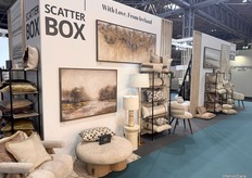 The booth showcases warm hues and plush textiles, complemented by custom-made curtains to create a cozy, inviting space.