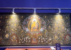 A hand-painted wall artwork with layered depth, portraying Buddha and other historical figures.